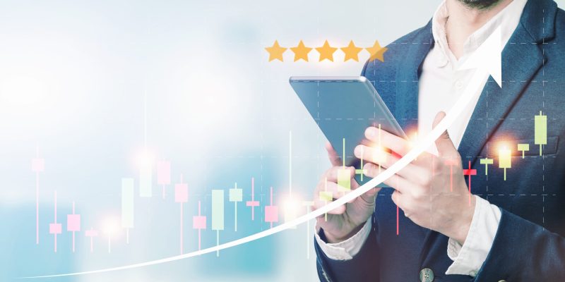 Double exposure of businessman using the tablet with cityscape and financial graph on blurred building background, Business Trading concept.